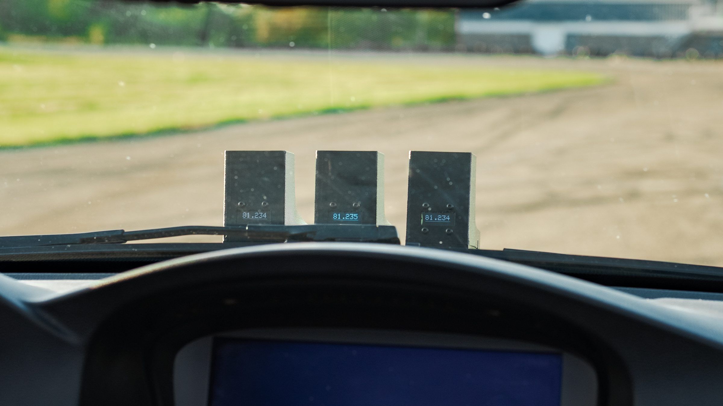 Three timing units on a car dash, seen from the driver's seat, each showing a lap time.