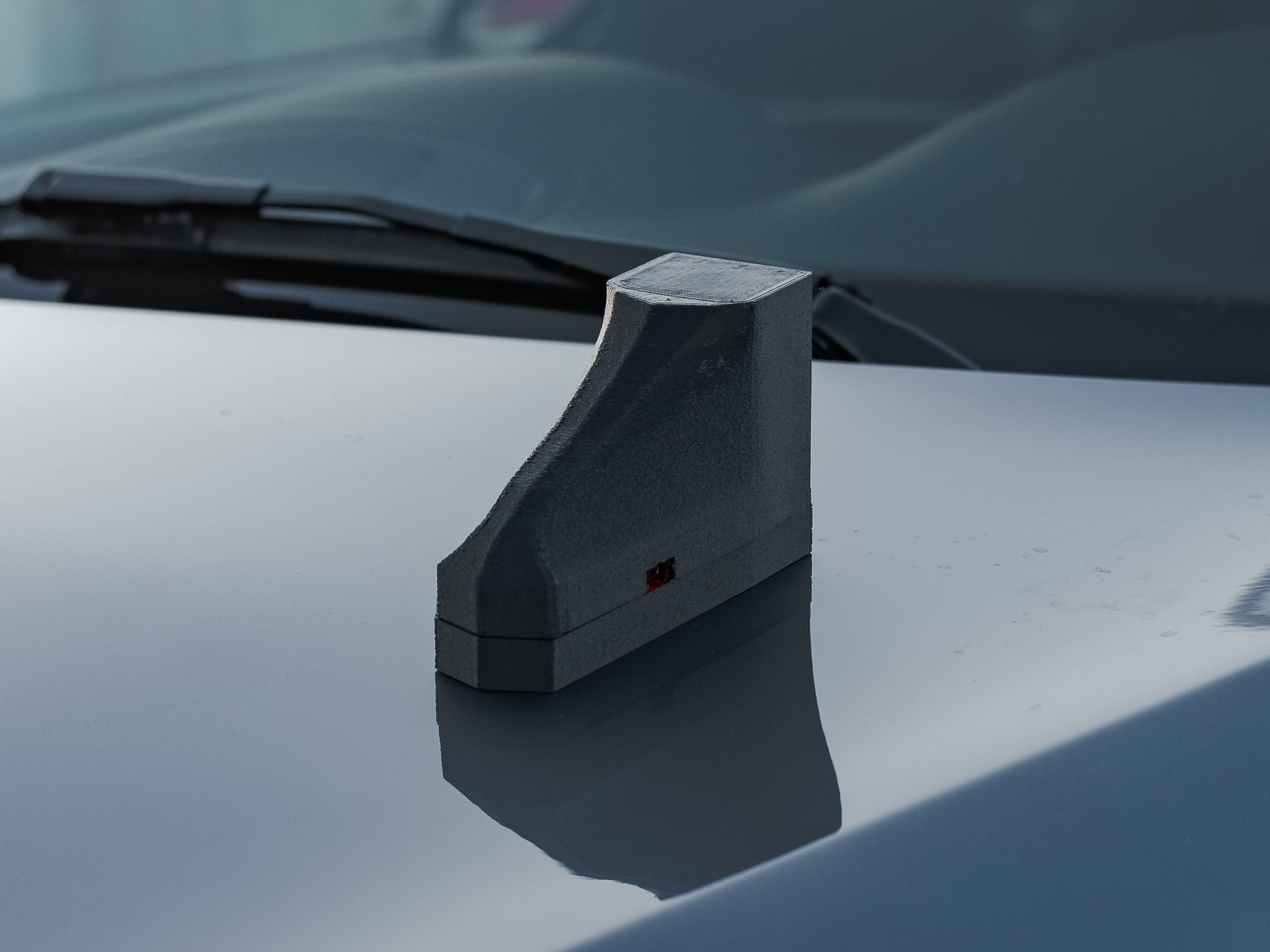 A timing unit on the hood of a car, in front of the windscreen wiper.